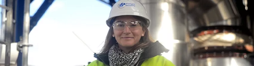 Chercheuse d'IFPEN souriante en casque et lunettes de sécurité sur un site industriel