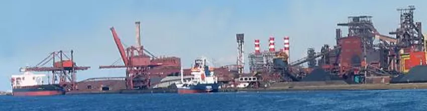 Complexe sidérurgique en bord de mer avec grues de déchargement et navires à quai
