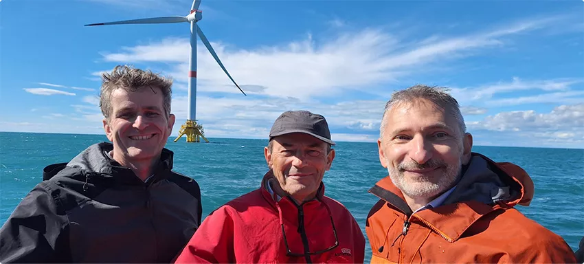 3 collaborateurs IFPEN (et GreenWits)- experts du domaine de l'éolien, avec en arrière plan et éolienne offshore