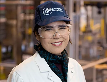 Photo d'une collaboratrice IFEN (portant une casquette et des lunettes de sécurité), dans une installation expérimentale