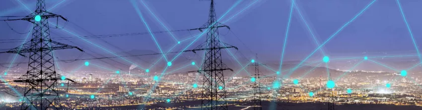 Pylônes électriques devant une ville illuminée, reliés par un réseau de points lumineux