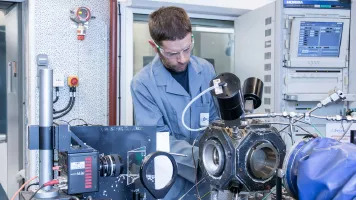 Chercheur en blouse manipulant un banc d'essai en laboratoire