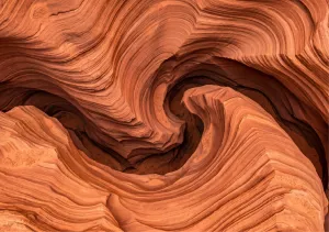 Strates de roche sédimentaire ocre aux plis tourbillonnants