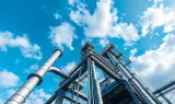 Structure métallique et canalisations industrielles sous un ciel bleu nuageux