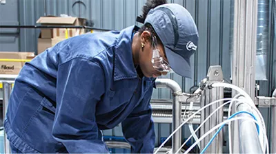 Collaboratrice IFP, portant des équipements de sécurité, et travaillant sur une installation expérimentale
