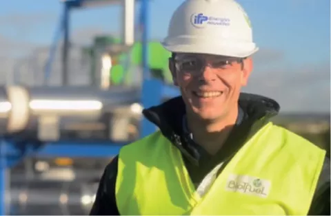Technicien souriant en casque et gilet de sécurité sur un site industriel