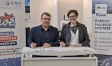 Un homme et une femme signant un document côte à côte devant des kakémonos