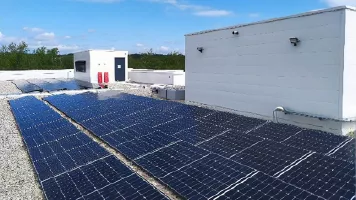 Panneaux solaires installés sur un toit terrasse à côté de locaux techniques
