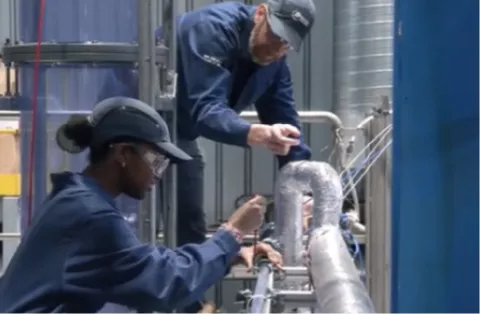 Deux techniciens en tenue de sécurité travaillant sur une installation industrielle
