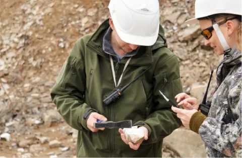 Deux géologues en casque examinant un échantillon de roche sur un site d'extraction