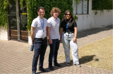 Trois jeunes stagiaires souriants devant un bâtiment