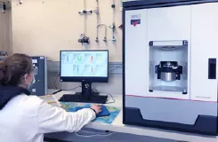 Chercheuse en blouse travaillant sur un ordinateur à côté d'un appareil d'analyse de laboratoire