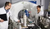 Deux chercheurs en blouse discutant devant une installation de laboratoire