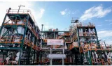 Unité industrielle aux structures métalliques et passerelles, sous un ciel bleu