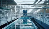 Bassins d'une station de traitement des eaux en intérieur, avec passerelles et canalisations