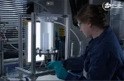 Chercheuse en gants manipulant un réacteur de laboratoire éclairé